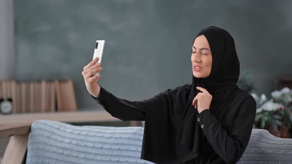 Happy Playful Asian Female Black Hijab Headscarf Posing Taking Selfie at Home