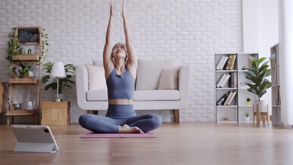 Asian woman practice yoga lotus pose to meditation at home.