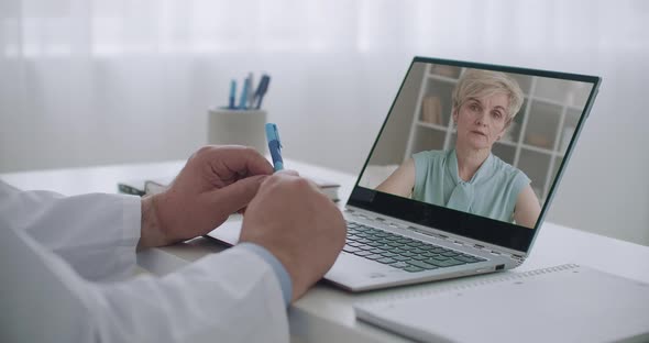 Elderly Woman Is Talking with Her Family Doctor By Video Call, Her Face on Screen of Laptop of