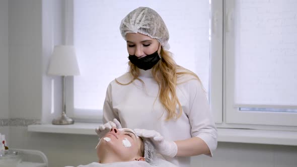 Doctor Cosmetologist in Rubber Gloves Apply Cream on the Face