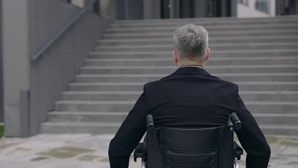 Backside View of Male Person in Suit Pushing Himself on Wheel Chair at Street