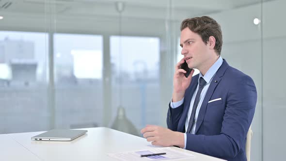 Young Businessman Talking on Smartphone in Modern Office 