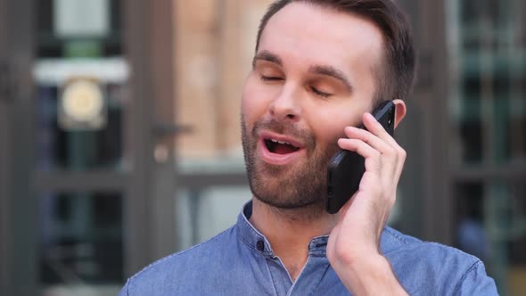 Young Man Talking on Phone Negotiating in Good Mood