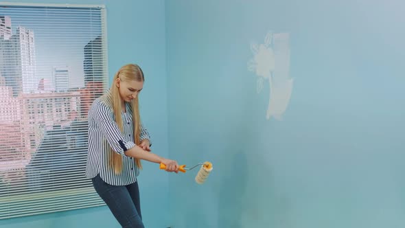 Woman Got Dirty in Paint. She Uses White Paint and Work with a Roller.