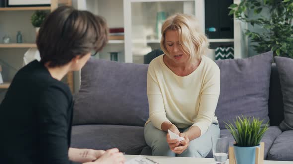 Senior Woman Talking To Therapist Discussing Problems in Modern Office