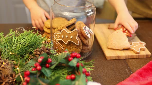Unrecognizable Child Hand Putting Homemade Christmas Cookies Into Glass Jar