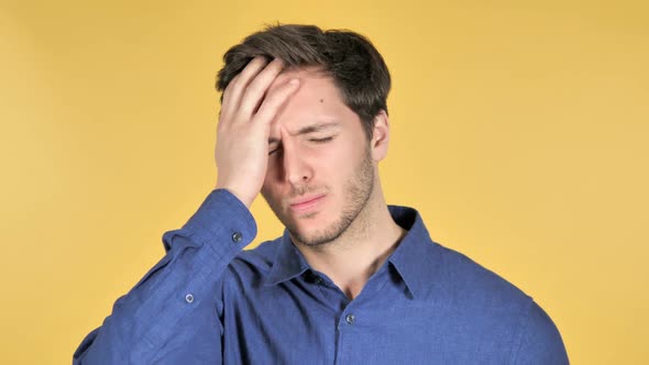 Casual Young Man with Headache on Yellow Background