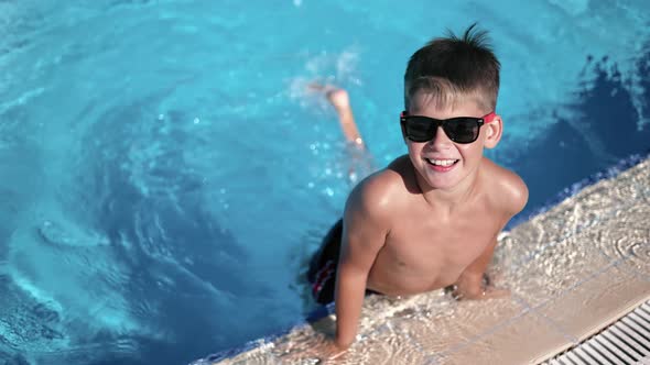 Relaxed Male Kid Posing at Swimming Pool Playing Legs at Bright Water Splash Slow Motion