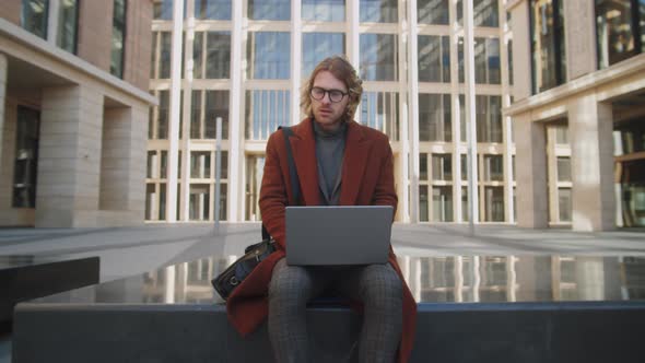 Elegant Caucasian Businessman Working on Laptop Outdoors