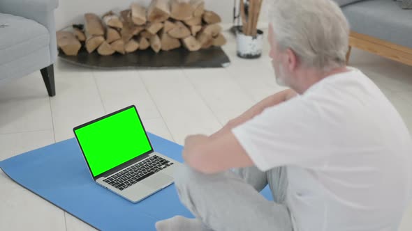 Rear View of Old Man Doing Yoga While Looking at Laptop with Chroma Key Screen