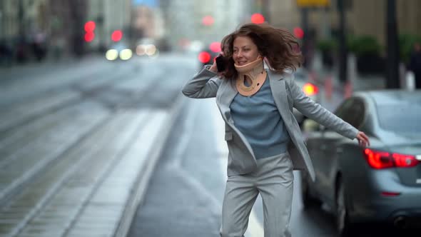 A Cheerful Middle-aged Woman in a Jacket Is Standing By the City Road Against the Background of