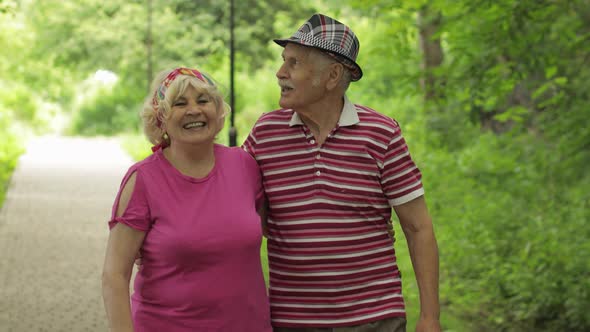 Senior Caucasian Couple Walking in Park Embracing. Elderly Man Walks with Woman. Husband, Wife