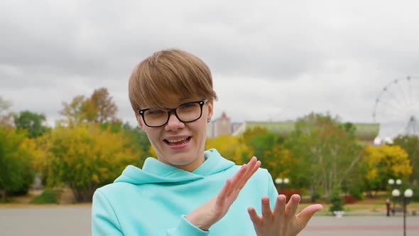 Young Woman Blogger in Eyeglasses is Broadcasting Outdoor Online and Talking About Events