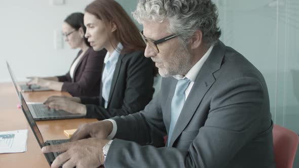 Row of Business Man and Women Sitting Together at Desk