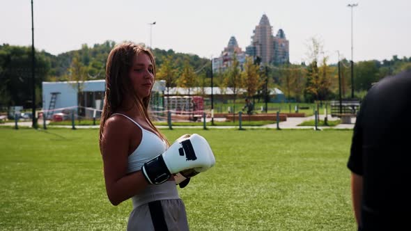 Boxing Training Outdoors  Young Woman with Long Hair Kicking the Target in Her Coaches Hand