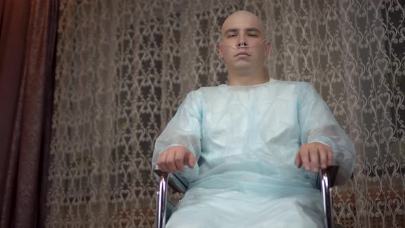 A Bald Young Man with Cancer Looks at the Camera and Prays. The Patient Folded His Arms and Prayed