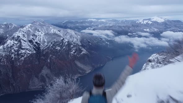 Hiker with backpack standing on mountain waving at Lake Como, Italy