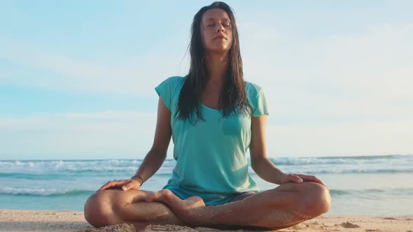 Yoga Woman Practices Yoga and Meditates in Lotus Position on Beach Sea