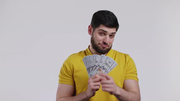 Happy Excited Man with Cash Money  USD Currency Dollars Banknotes on White Wall