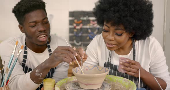 Black Couple Decorating Plate in Workshop During Class