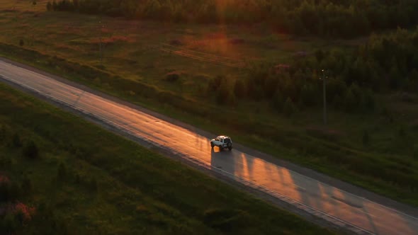 Aerial View of a Car Driving on the Road at Sunset