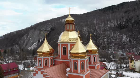 Aerial Drone View of Ukrainian Church with Golden Domes in Carpathian Village in Winter