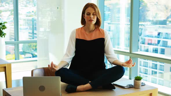 Female executive meditating at her desk