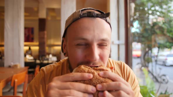 Young Bearded Man Eating Vegan Burger. Healthy Ethical Food Diet Concept. Slowmotion Portrait Shot