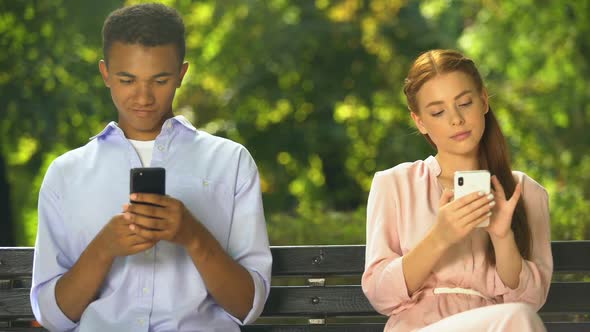 Male and Female Teenagers Sitting on Bench and Chatting on Smartphones, Problems