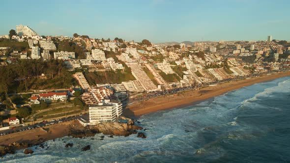 Aerial view flying towards Reñaca affluent cityscape resort waterfront and golden beach coastline