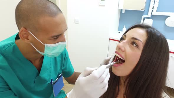 Close up of dental assistant examining woman's teeth