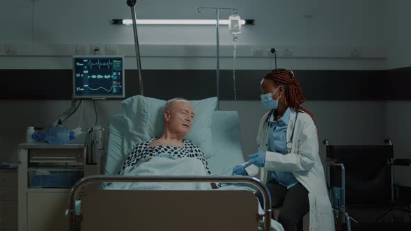 African American Doctor Talking to Sick Patient in Hospital Ward