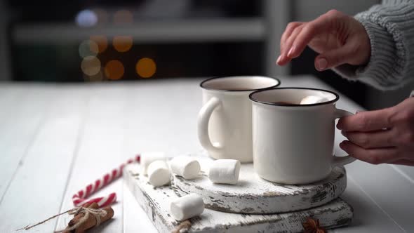 Woman Throwing Marshmallow Into Cocoa Cup