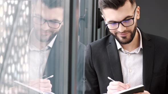 Businessman Putting Notes Standing Near Window at Office