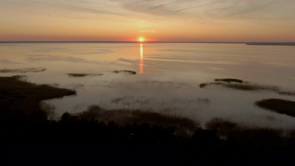 Aerial Shooting of Colorful Sunset Over a Large Beautiful Lake and Pine Forest