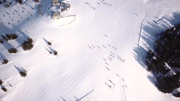Aerial view of People Skiing and snowboarding on hill, Ski Resort. Drone flies over Skiers Skiing do