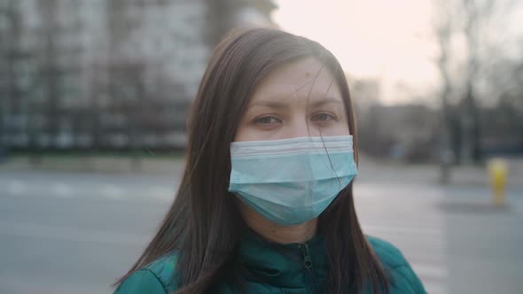 A Young Girl in Glasses and Medical Mask Stands on the Street