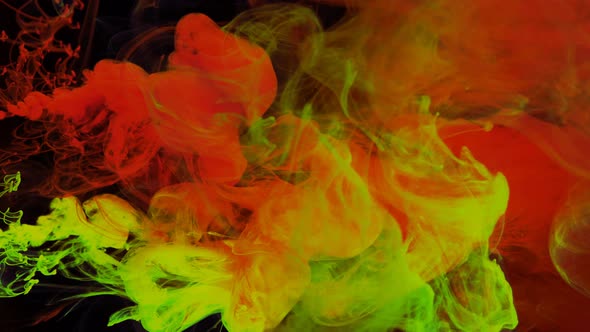 Stream of Red and Yellow Paint Dissolves in a Transparent Space on a Black Background alt