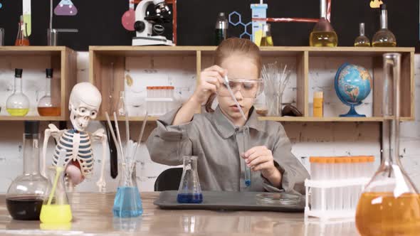 Laboratory Experience in a Chemistry Lesson a Girl in Protective Glasses Pours a Blue Liquid Into a