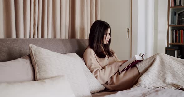 Woman Reading a Book Lying on Bed at Home