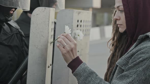 Woman Putting Flowers into Riot Policemen Shields