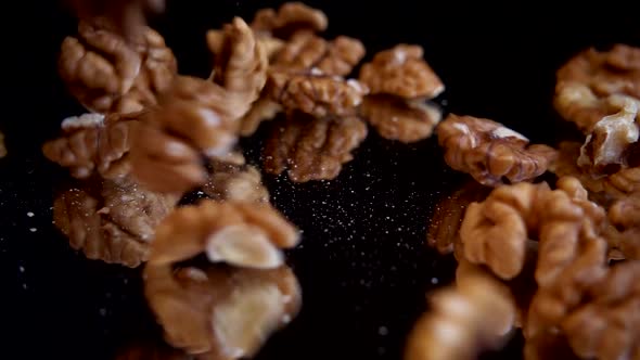 Walnut kernels fall on a black mirror surface