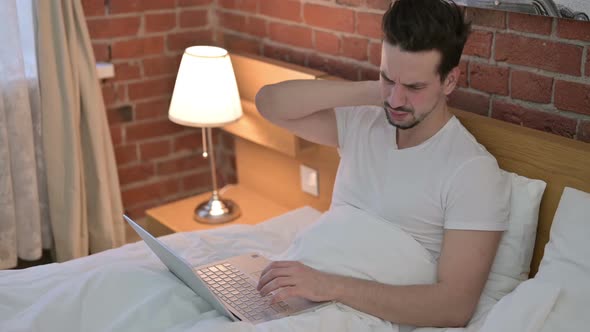 Young Man Having Neck Pain While Working on Laptop in Bed