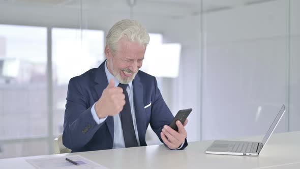 Old Businessman Celebrating Success on Smartphone 