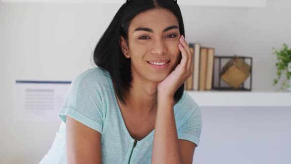 Portrait of mixed race gender fluid person looking at camera and smiling at home