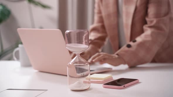 Woman working against the clock on her laptop, due date deadline concept, time control with an hourg