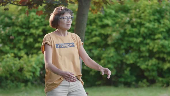 Woman Plays Frisbee on Grass Lawn