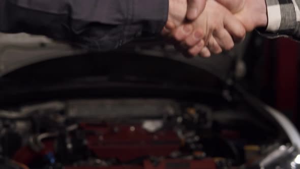 Close Up Shot of Mechanic and Customer Shaking Hands in an Auto Repair Shop