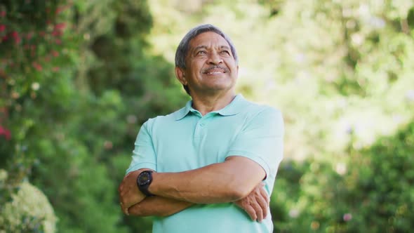 Video of happy biracial senior man looking at camera in garden