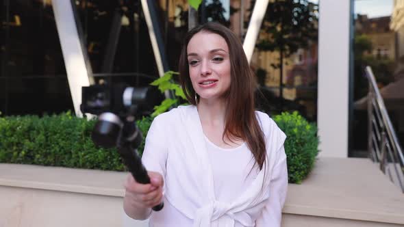 Woman Filming Video On Camera Near Modern Office Building